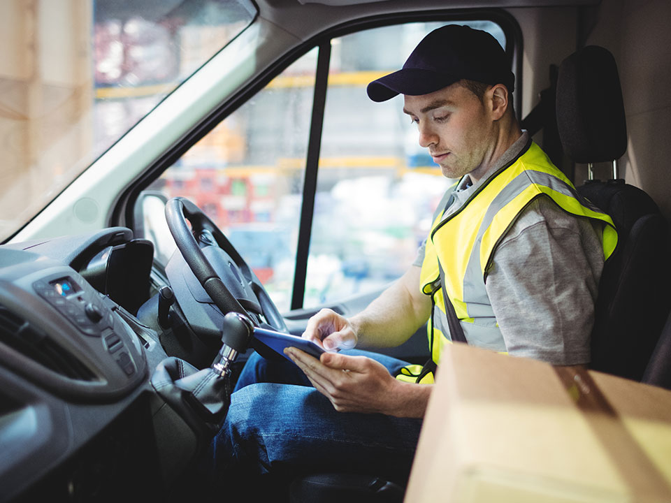 Delivery driver in van using a tablet computer